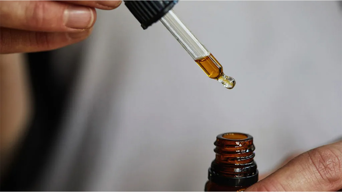 Man holding CBD oil on one hand and a dropper on the other